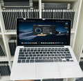 Laptop on a white surface with a blurred background of stacked electronic devices