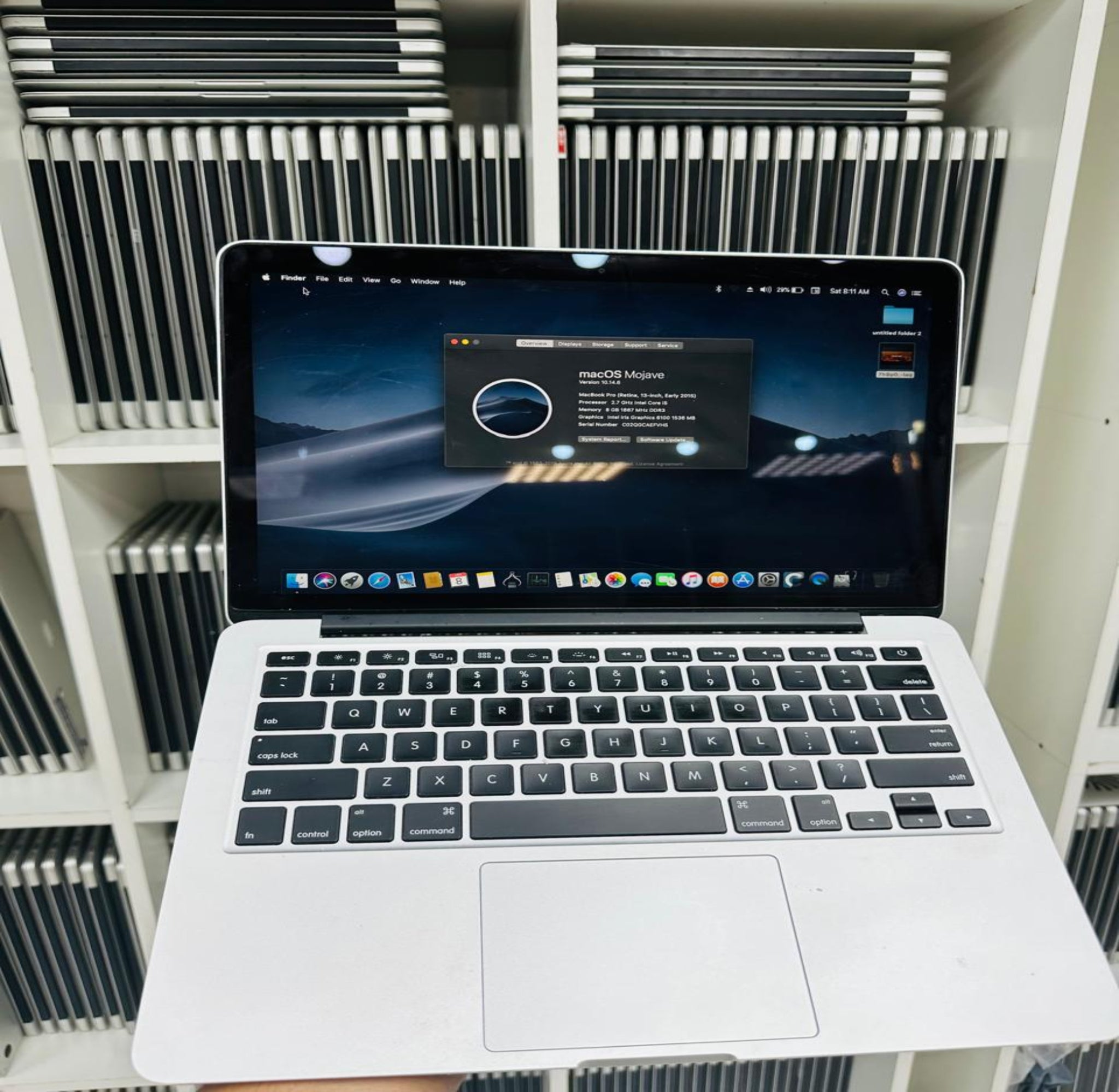Laptop on a white surface with a blurred background of stacked electronic devices