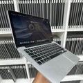 Laptop held in front of a shelf with multiple laptops